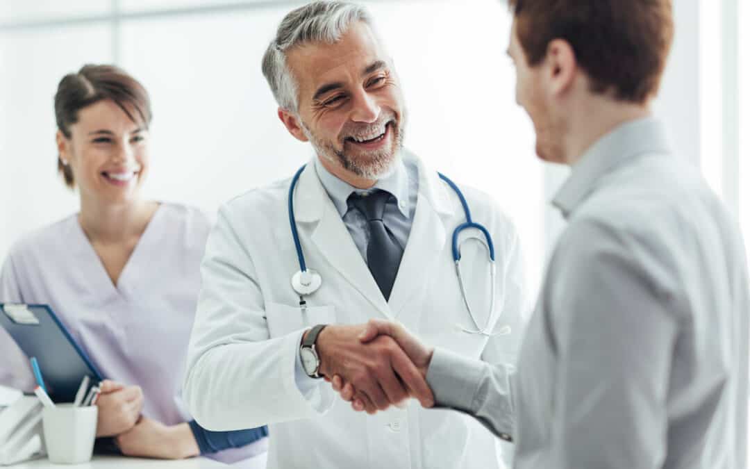 A male doctor and his male patient smiling and shaking hands