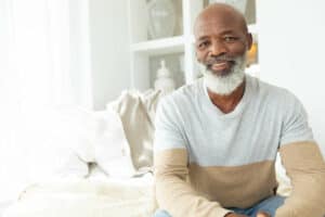 Middle aged African American male sitting on his bed and smiling at the camera