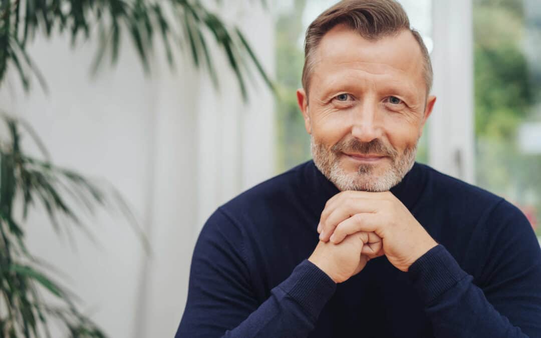 Middle aged man sitting and smiling at the camera