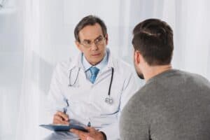 Male doctor asking his male patient medical questions